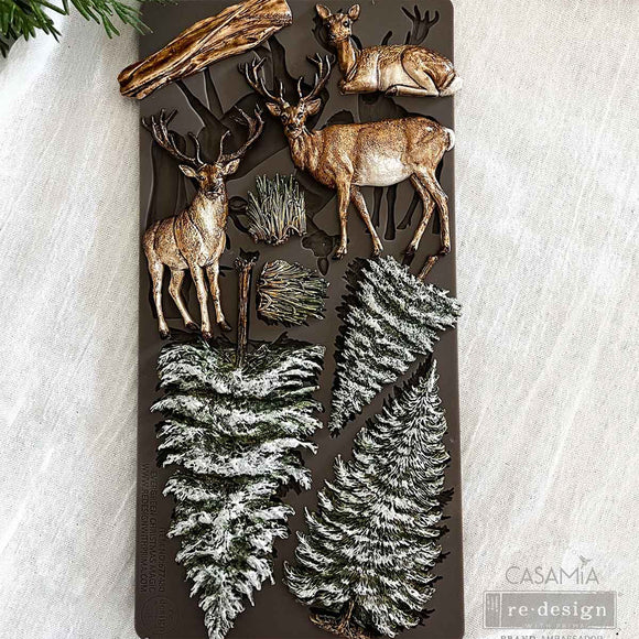 Decorative wall art with deer and pine tree designs on a textured surface.
