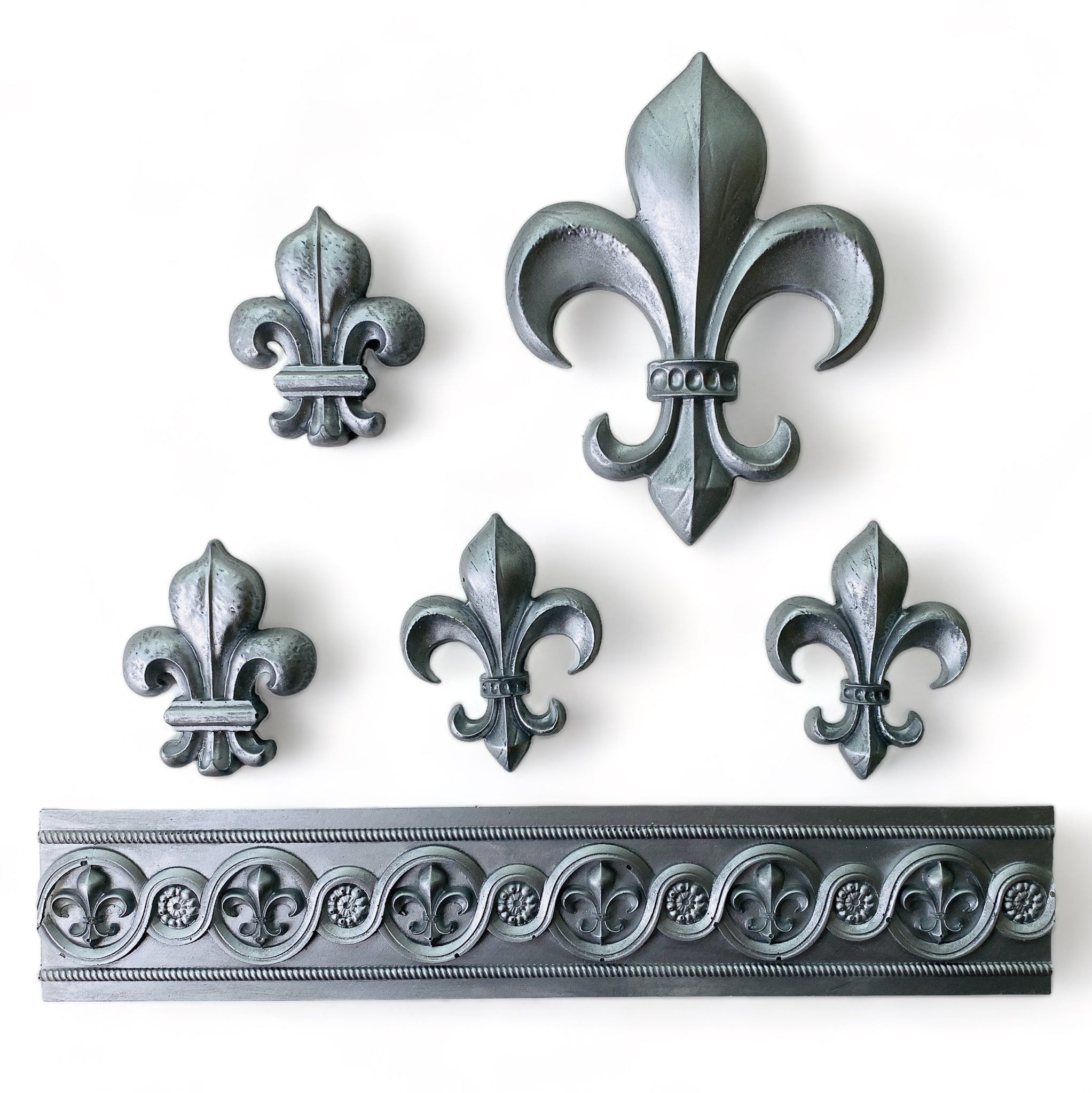 Silver colored silicone mould castings from ReDesign with Prima's Fleur De Lis En Or  silicone mould are against a white background.