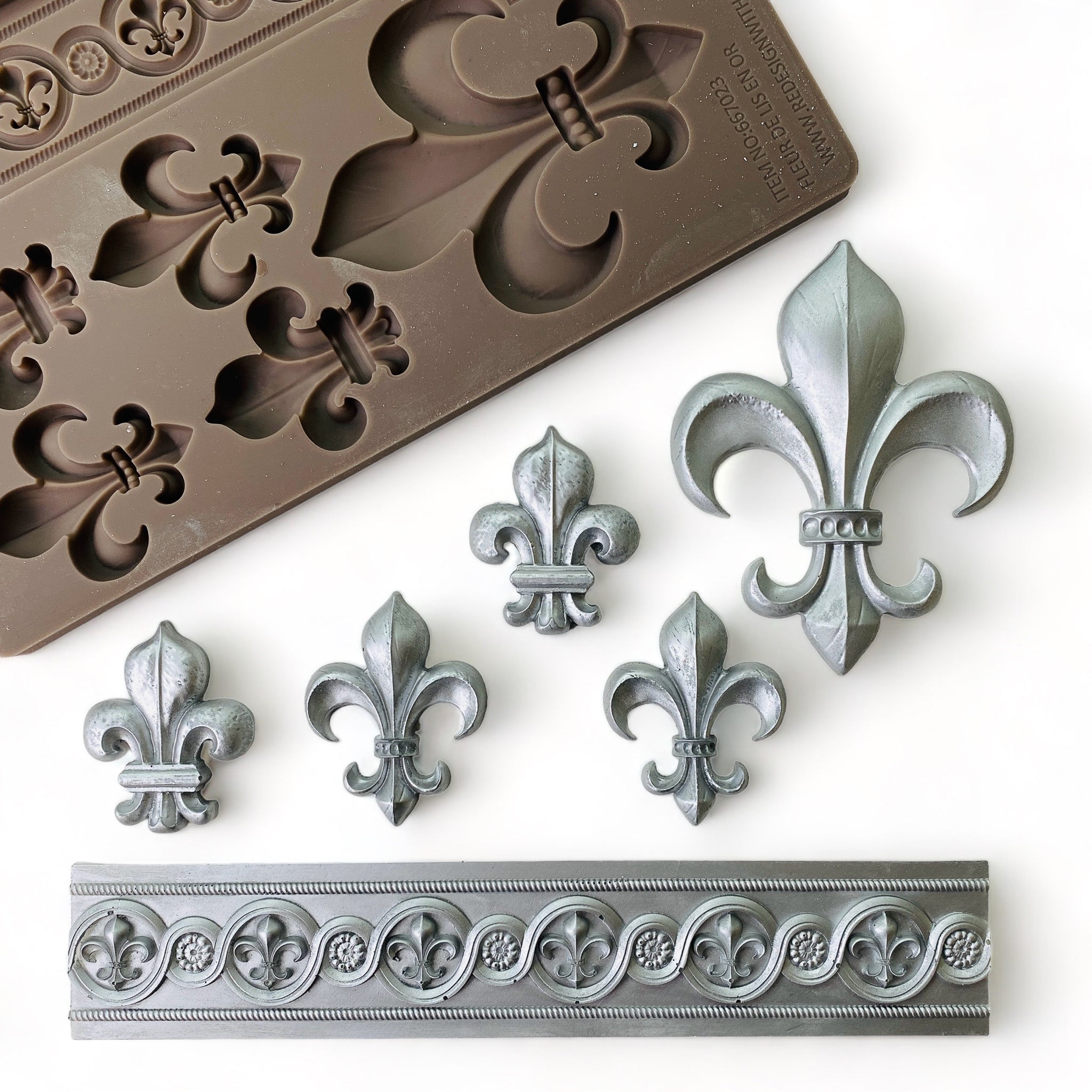A brown silicone mould and its silver colored castings of 5 fleur de lis and a fleur de lis border are against a white background.