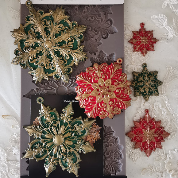 Decorative snowflake molds in gold, red, and green on a textured surface.