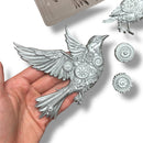 A hand is shown holding a bird casting created from ReDesign with Prima's Gears of Flight silicone mold against a white background with other castings.