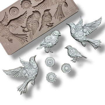 A silicone mold and silver colored castings featuring 4 birds adorned in cogs and gears, along with 3 separate gears are against a white background.