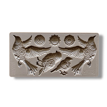 A silicone mold featuring 4 birds adorned in cogs and gears, along with 3 separate gears is against a white background.