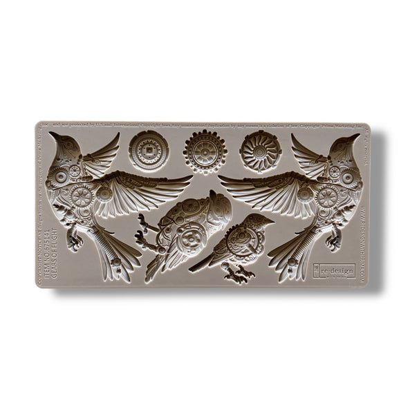 A silicone mold featuring 4 birds adorned in cogs and gears, along with 3 separate gears is against a white background.