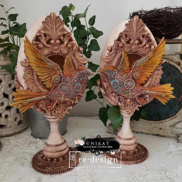 Two decor eggs created by Unikat feature colorful castings of ReDesign with Prima's Gears of Flight silicone mold on them.