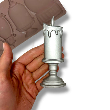 silver candle casting held by a hand with a silicone mold in the background