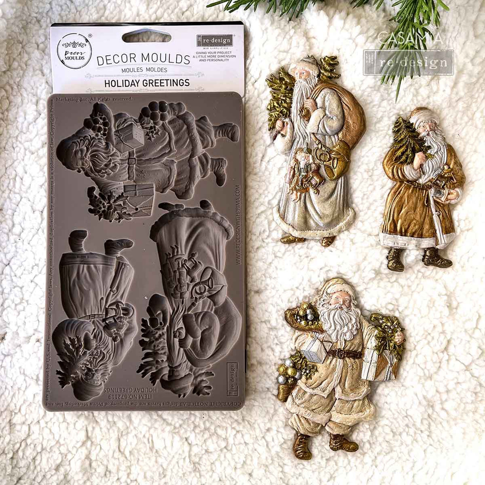 A package of ReDesign with Prima's Holiday Greetings silicone mold and colorful castings created by Casamia are against a white Sherpa blanket background.