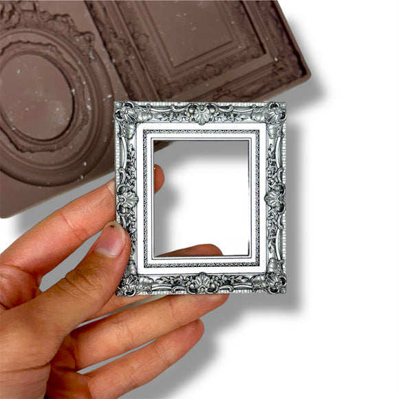 Hand holding a small ornate silver mirror with a silicone mold in the background