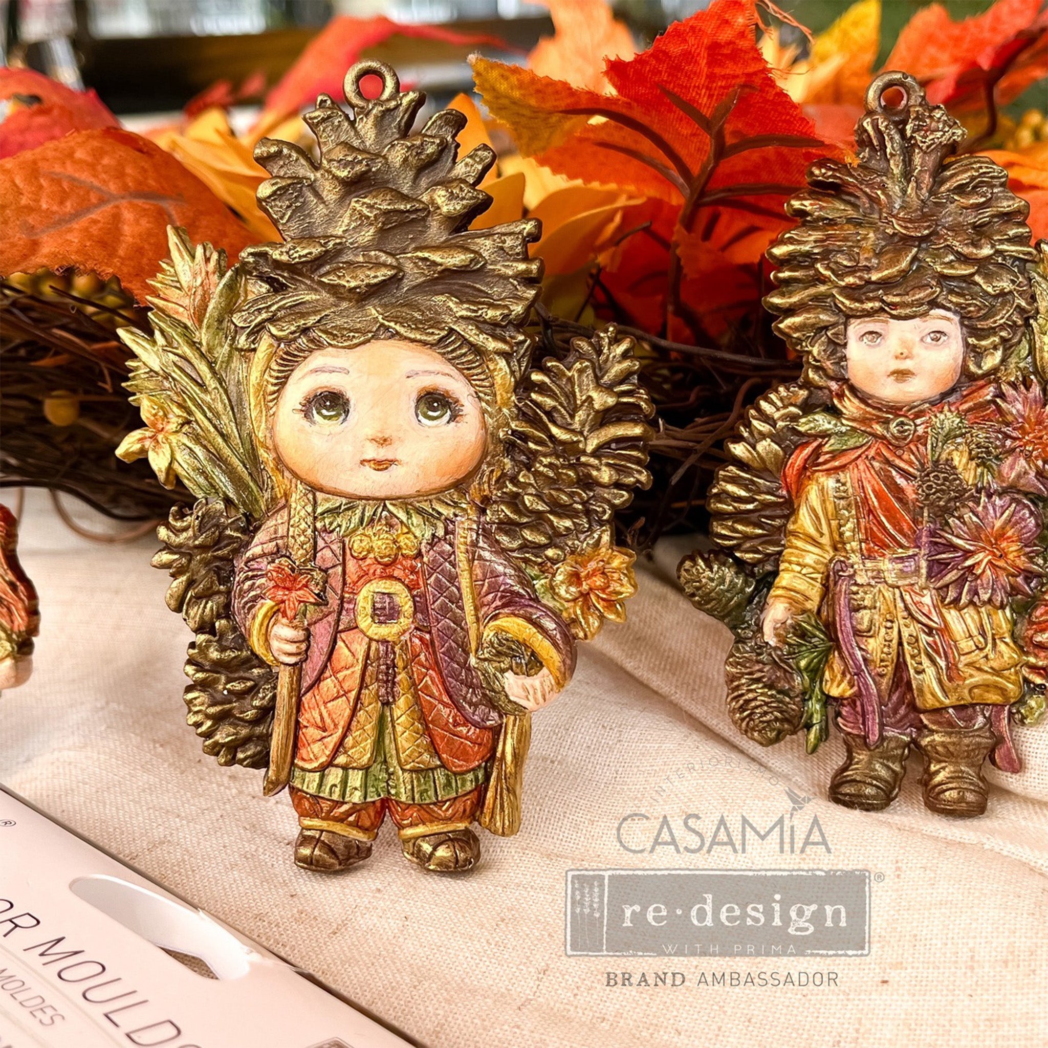 Colorful castings created by Casamia that are made from ReDesign with Prima's Pinecone Dolls silicone mold are shown against some silk fall leaves.