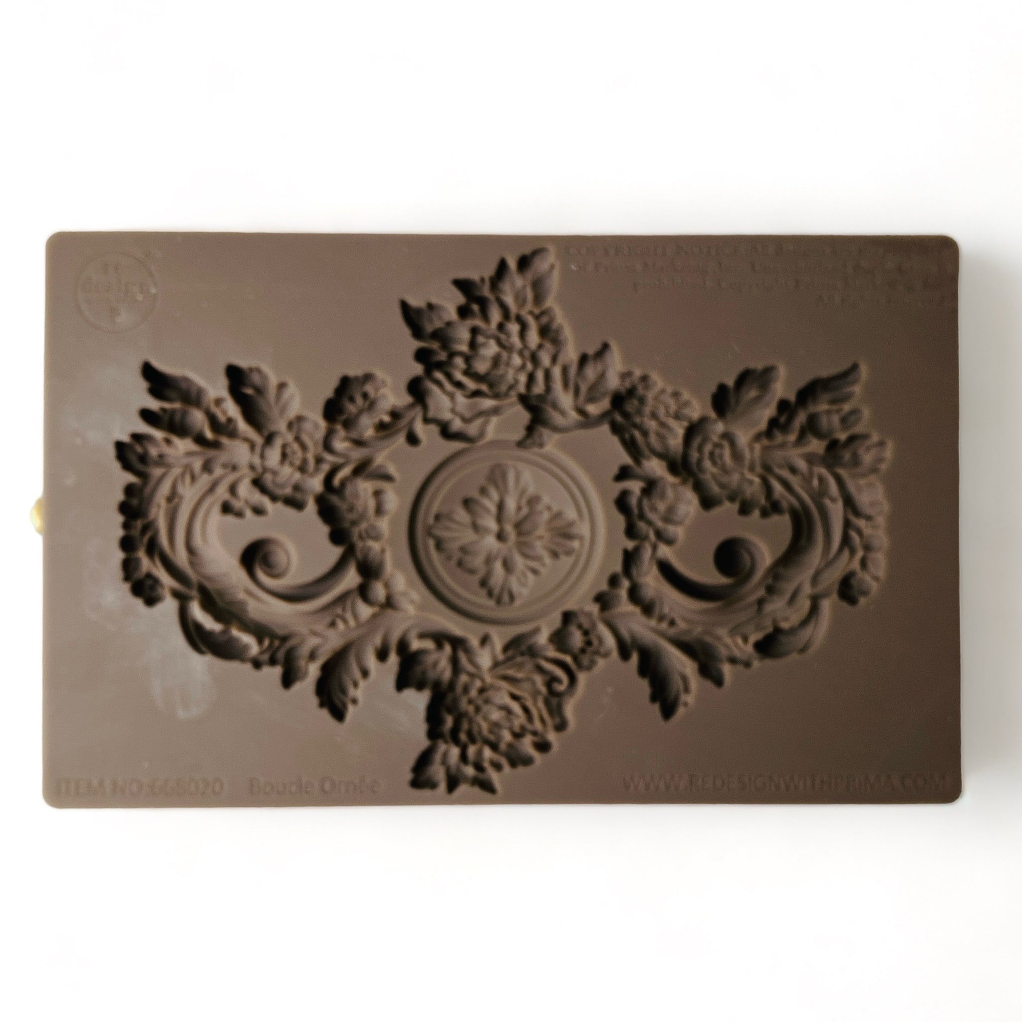 A brown silicone mold of a large ornate floral accented medallion center piece are against a white background.