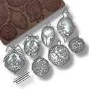 Decorative silver ornaments with intricate designs next to a mold on a white background