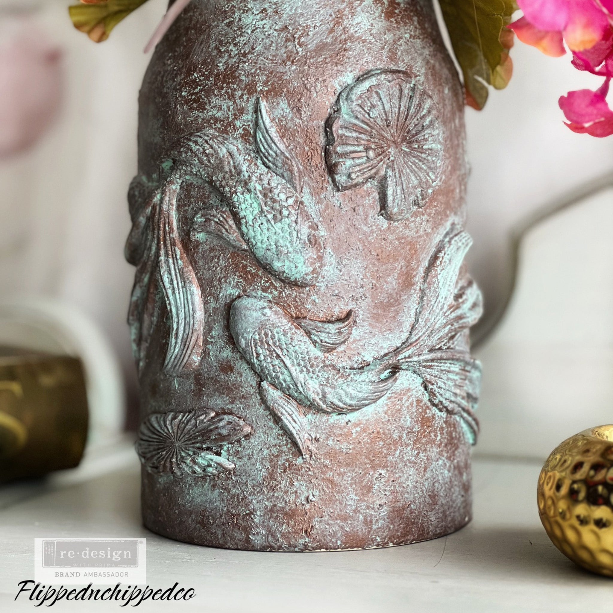 A ceramic vase created by Flipped n Chipped Company is painted patina green and brown and features castings made from ReDesign with Prima's Siamese Splendor silicone mold.