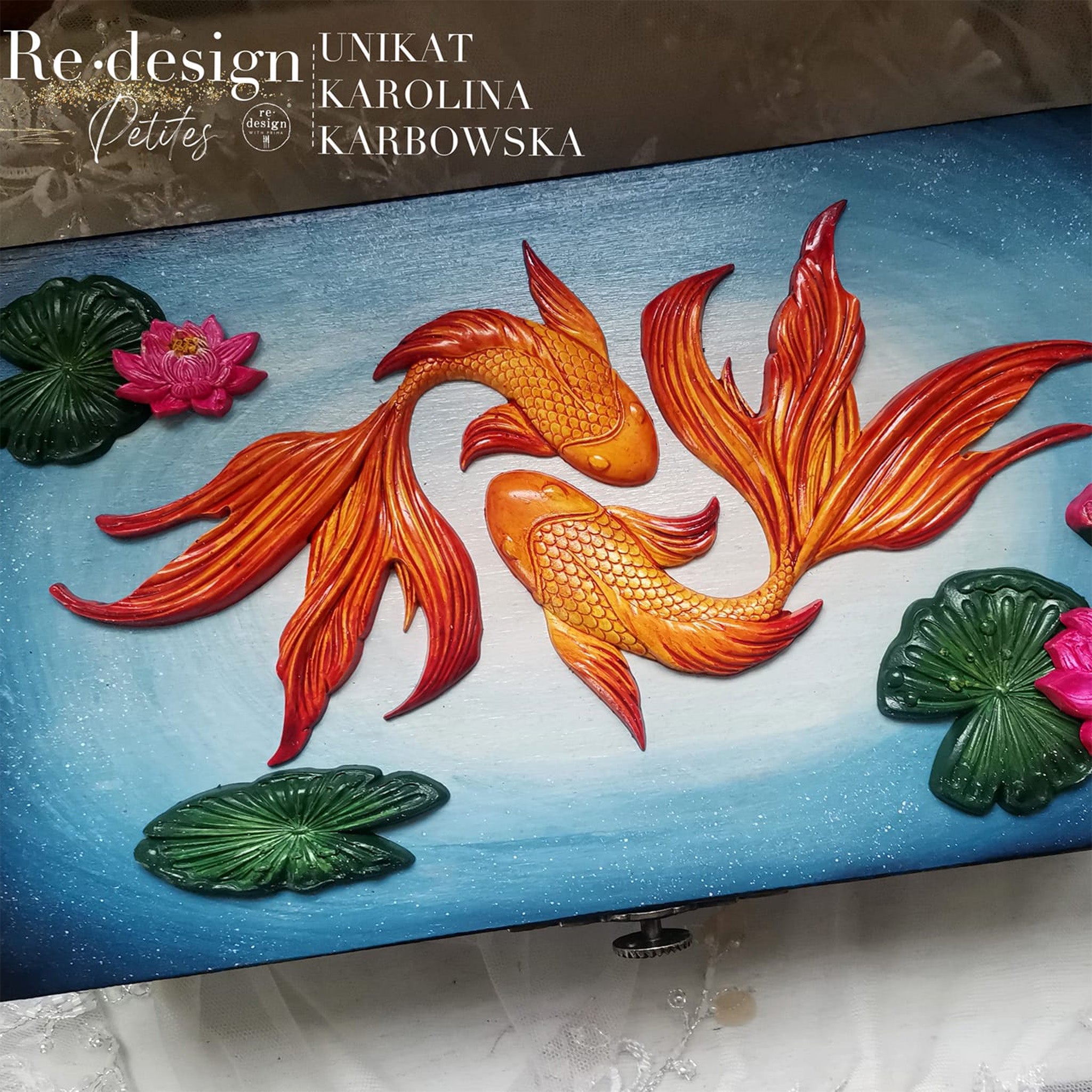 A close-up of a wood box refurbished by Unikat Karolina Karbowska is painted a blend of blue and white and features colorful castings of ReDesign with Prima's Siamese Splendor silicone mold.