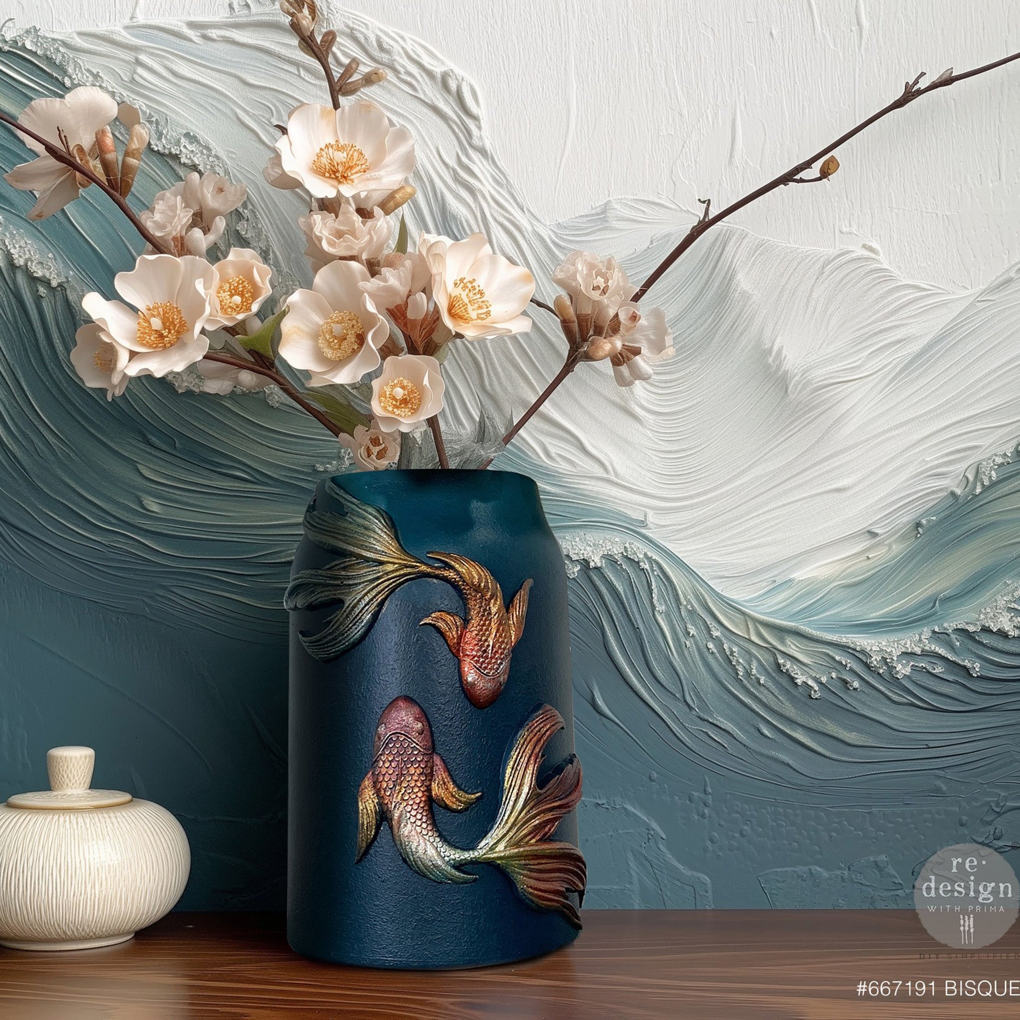 A vase is painted blue and features ReDesign with Prima's Siamese Splendor silicone mold fish castings painted in rustic patina colors.