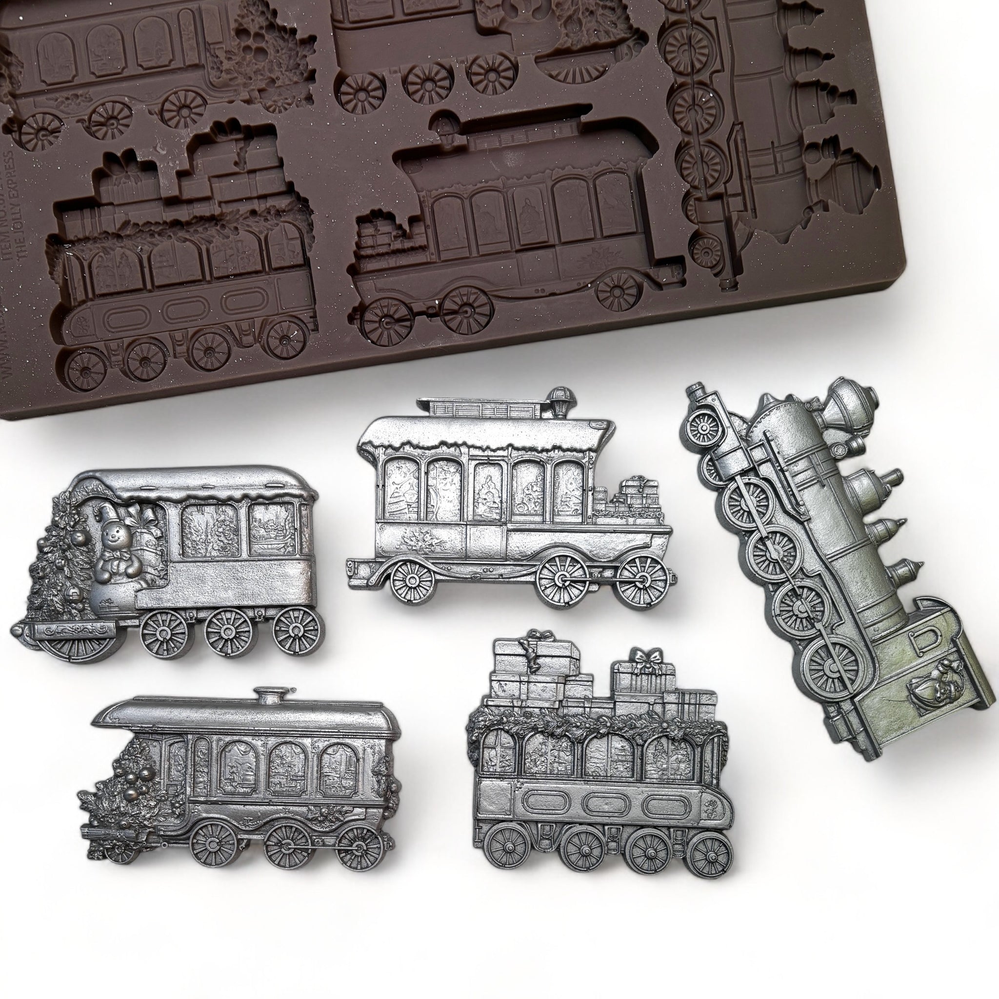 A brown silicone mold and silver colored castings of 5 holiday train cars are against a white background.