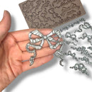 silver resin bow-shaped mold and castings on a white background