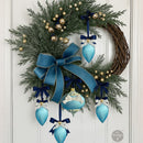 Evergreen door wreath with a large teal bow and blue ornaments with small bow details—festive bow decor inspiration for Timeless Ties.