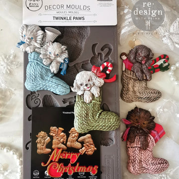 A package of ReDesign with Prima's Festive Cardinal Cheer silicone mold and colorful castings are against a white lace background.