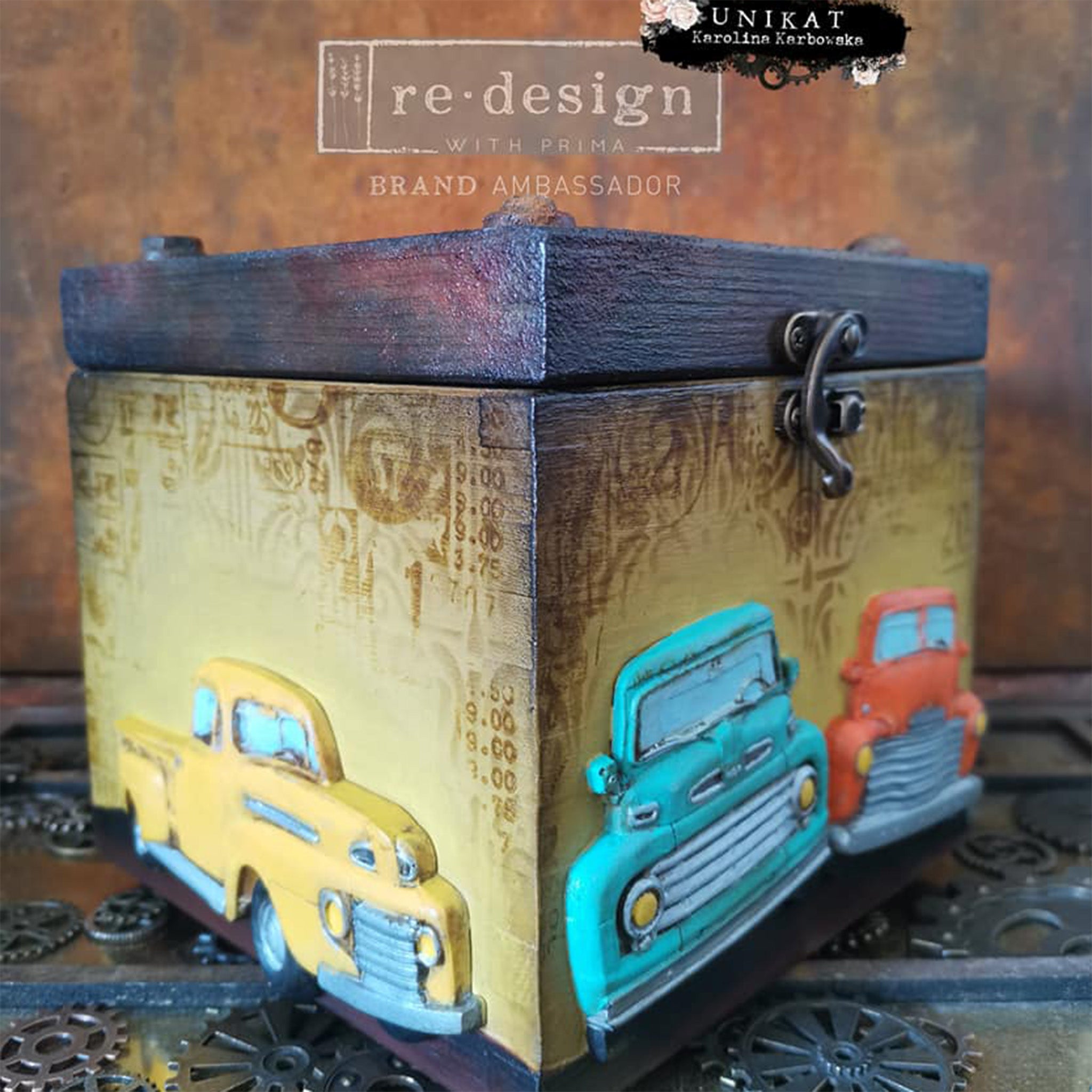 A small wood box refurbished by Unikat is painted pale yellow with a dark stain lid features colorful castings from ReDesign with Prima's Truck silicone mold on the sides.