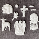 White resin castings from Eternal Spring Faith mold including lamb, angel scene, cross with lilies, floral egg frame, Bible and Joyful Easter words