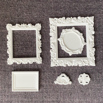 Miniature Grace Frames silicone mold castings—white ornate square and oval vintage frames with crest and medallion embellishments
