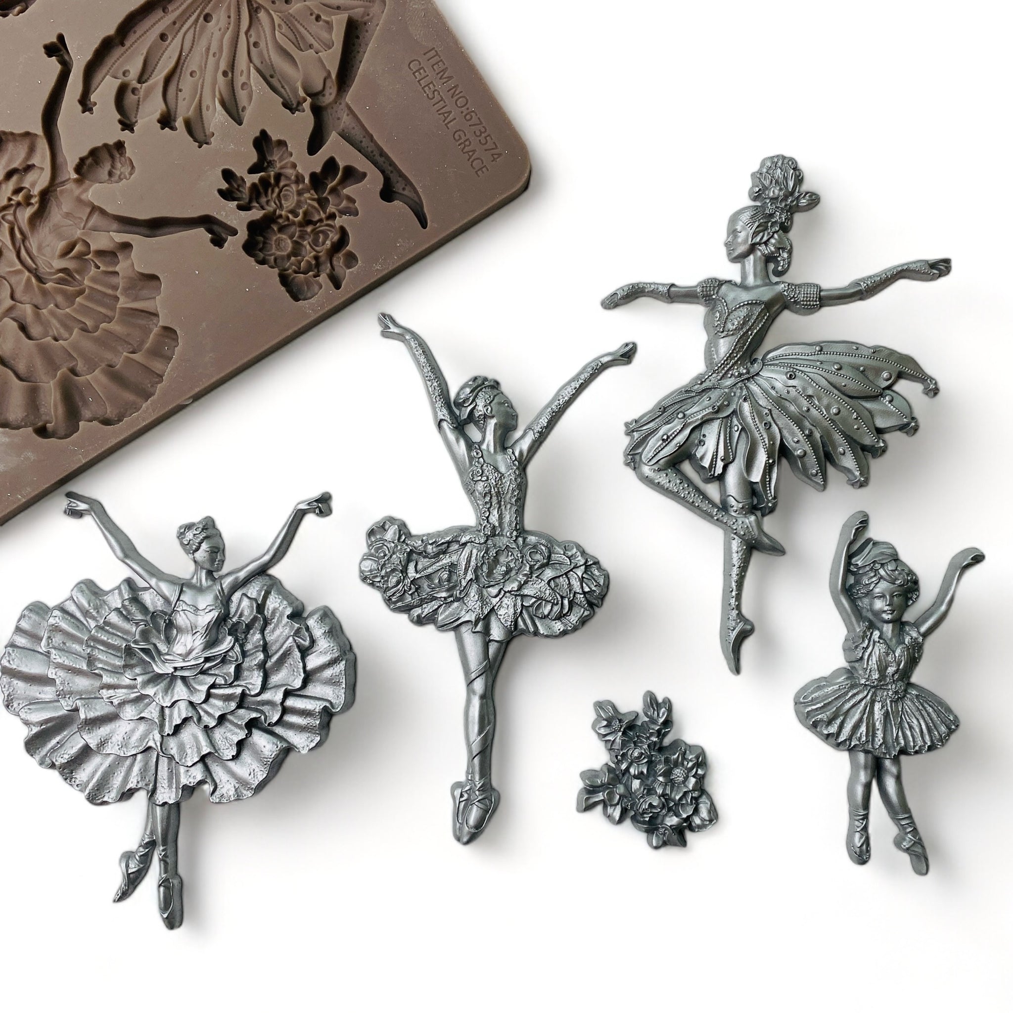 A brown silicone mold and silver colored castings of 3 adult ballerinas, a child ballerina, and a bouquet of flowers are against a white background.