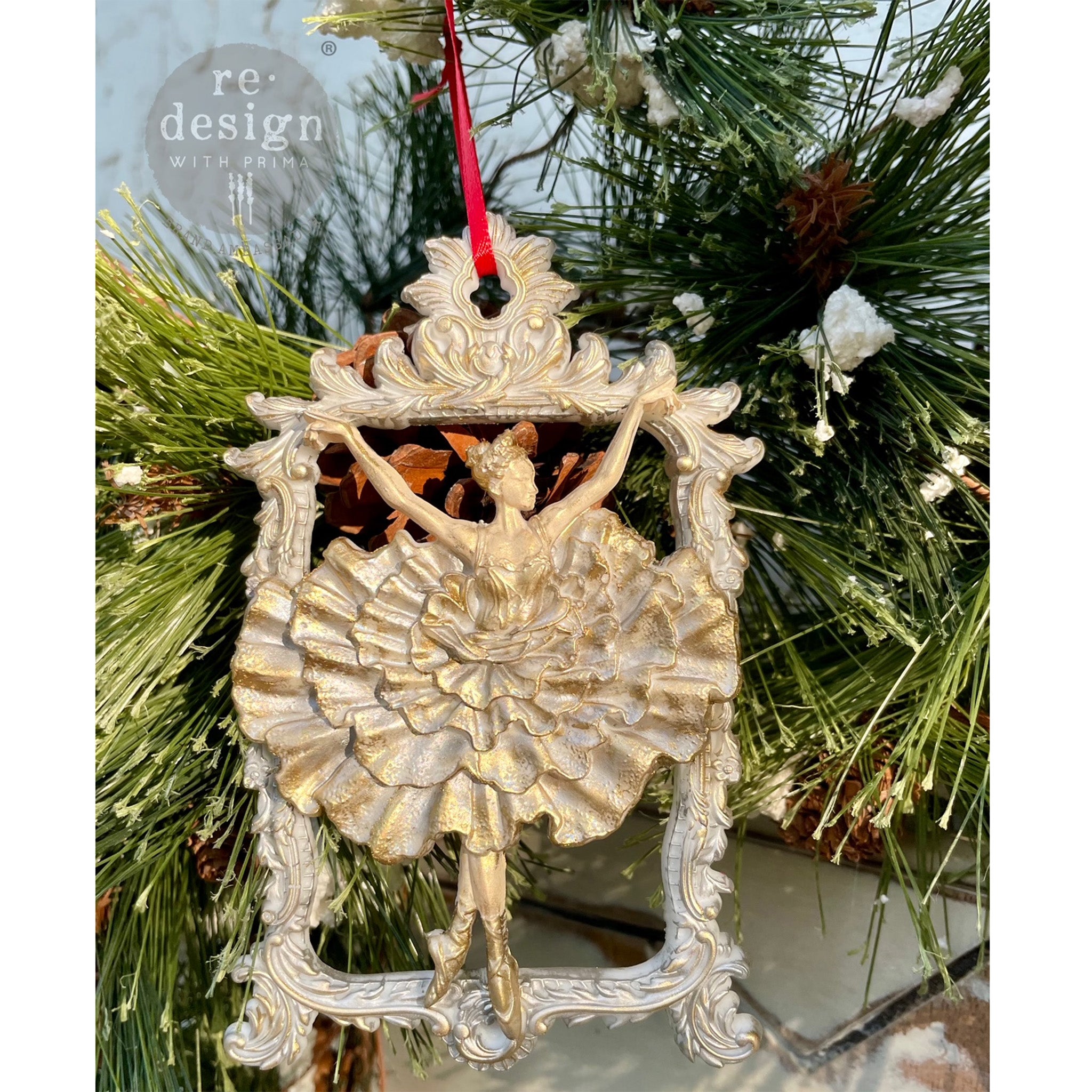 A gold colored ornament created from ReDesign with Prima's Celestial Grace silicone mold is hanging on pine.