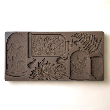 A brown silicone mold featuring 4 Victorian cloches with plants and butterflies in them, and ferns and snails is against a white background.
