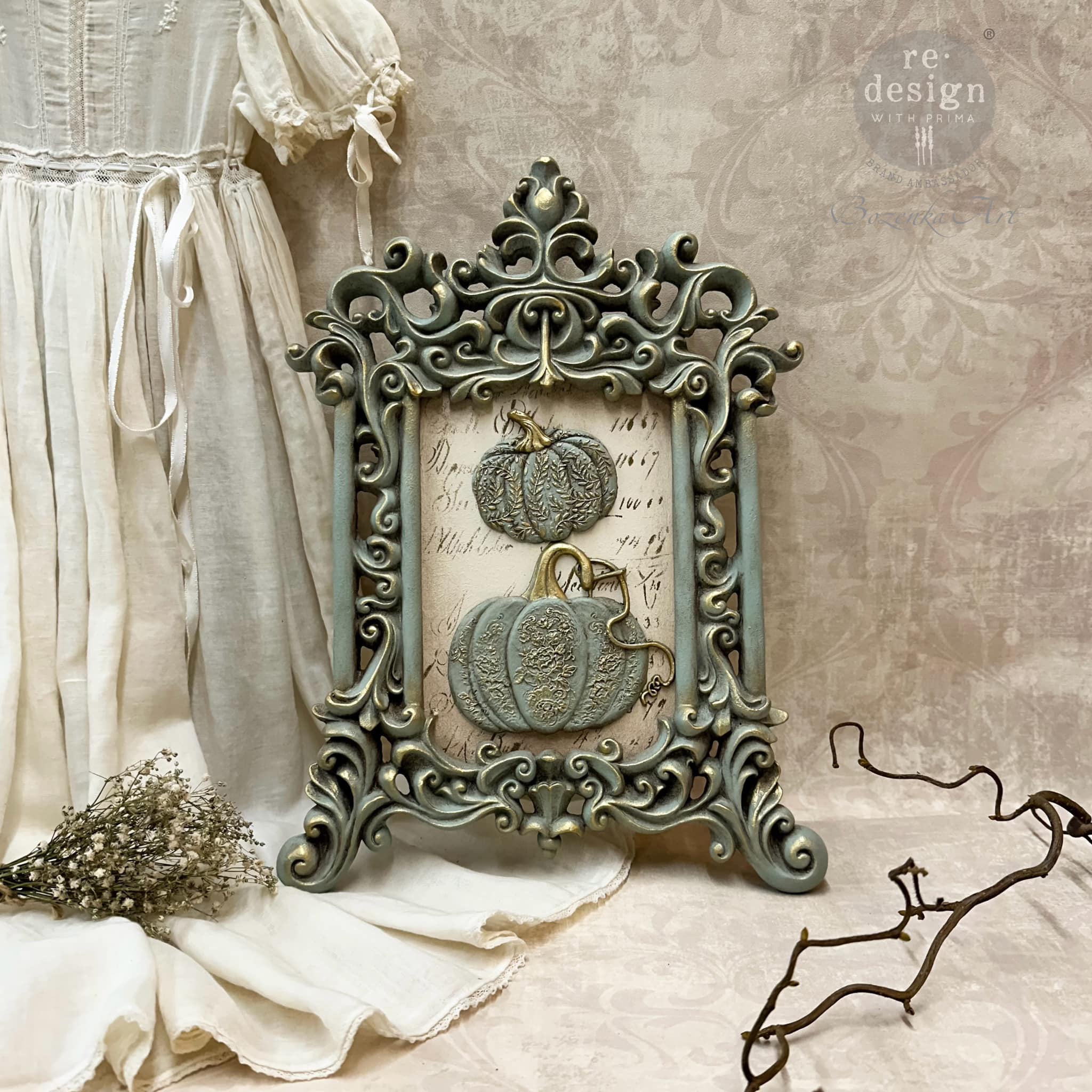 An ornate photo frame features ReDesign with Prima's Falling for Fall silicone mold castings painted a light sage green with gold accents inside.