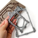 Decorative silver frame held by a hand with mold in the background