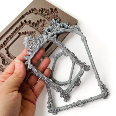 Decorative silver frame held by a hand with mold in the background