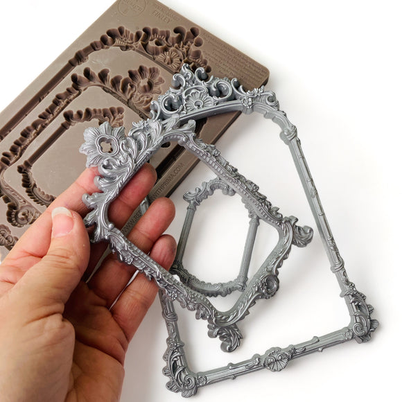 Decorative silver frame held by a hand with mold in the background