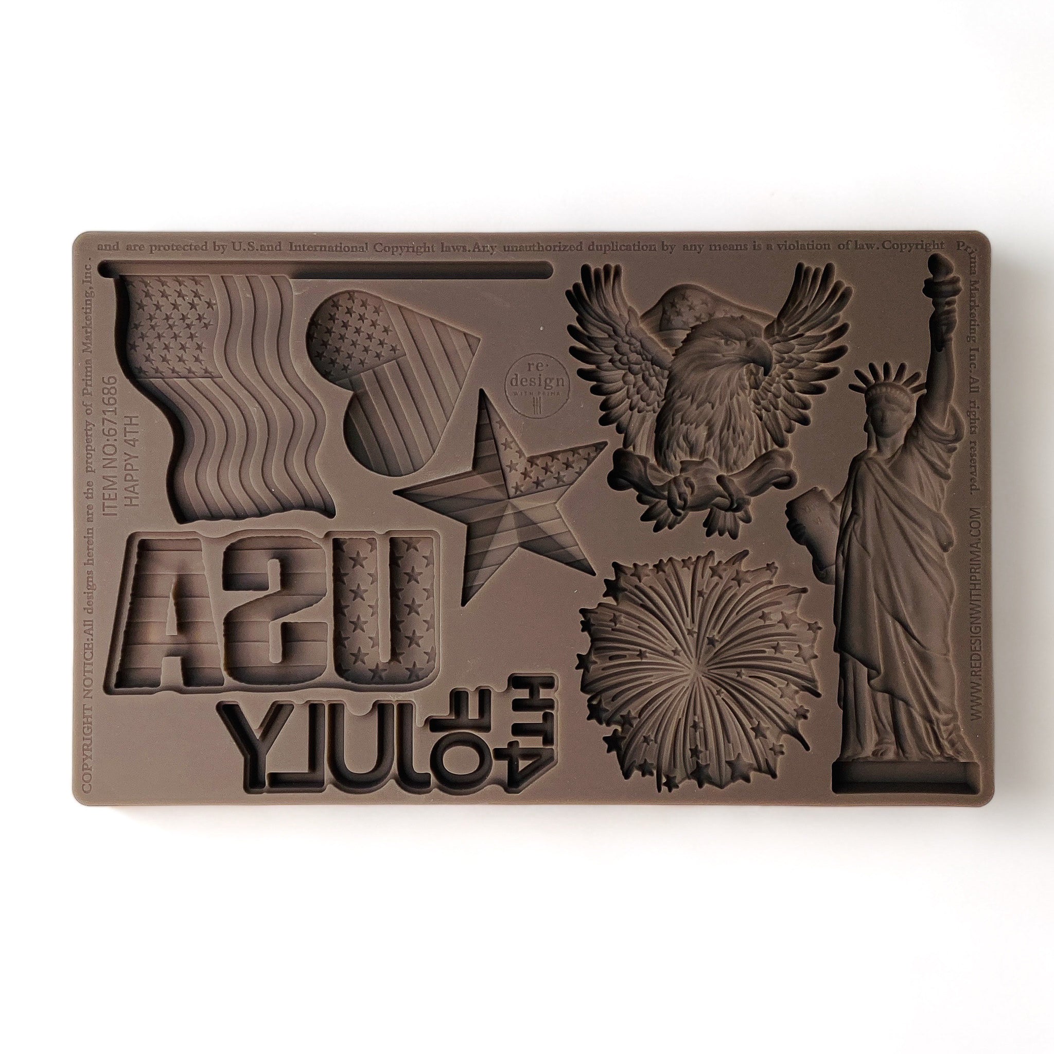 A brown silicone mold against a white background features the Statue of Liberty, an American eagle, fireworks, and other patriotic designs.