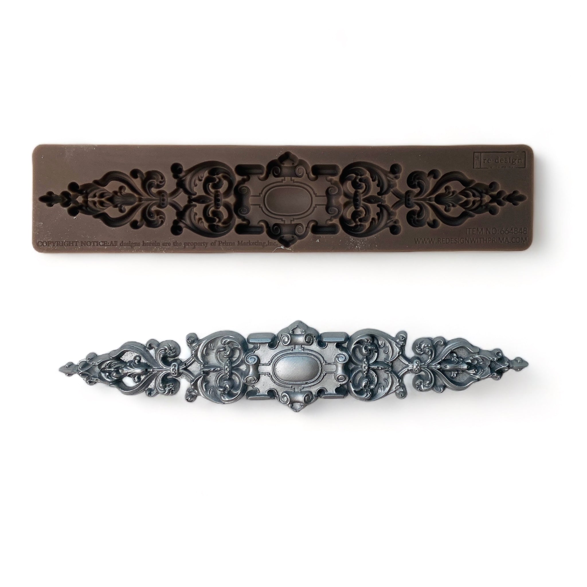 A brown silicone mold and silver colored casting of a long, ornate, scroll decorative center medallion are against a white background.