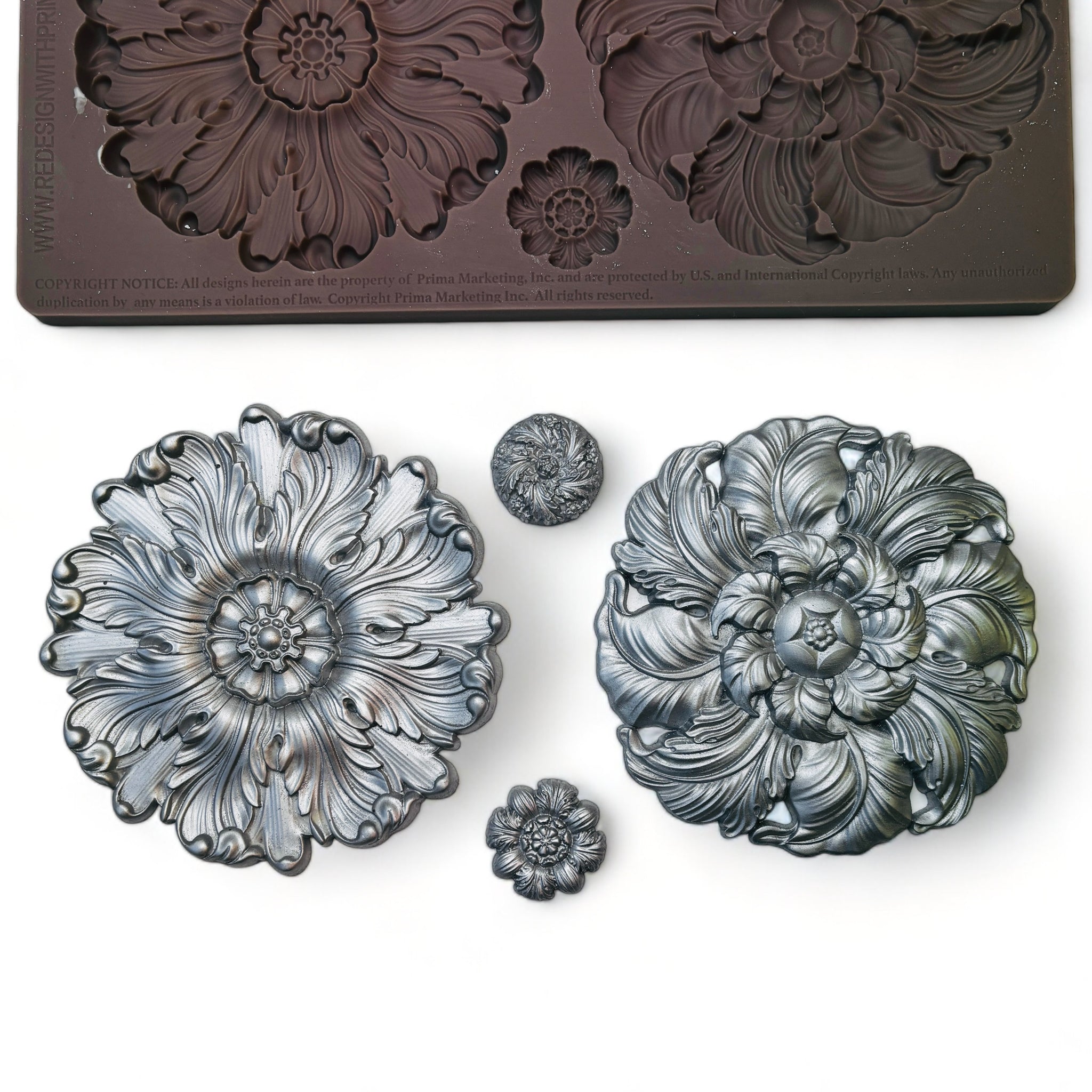 A brown silicone mold and silver colored castings of 2 large and 2 small floral medallions are against a white background.