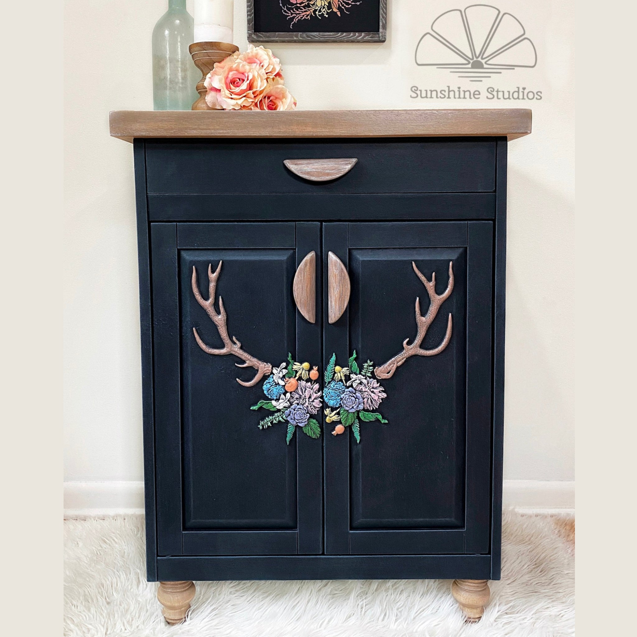 A small buffet cabinet refurbished by Sunshine Studios is painted black with natural wood accents and features ReDesign with Prima's Logger's Lodge silicone moulds on the doors.