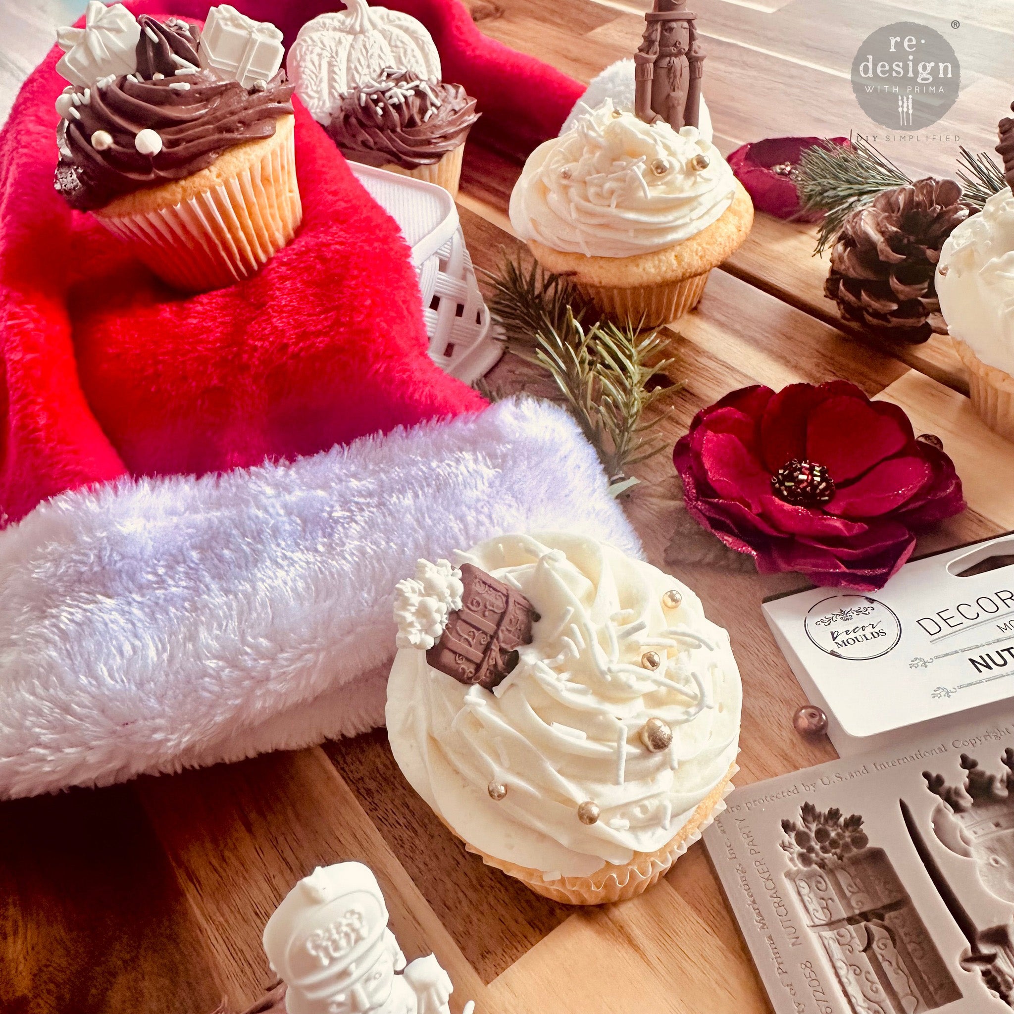 Cupcakes on a wood table with a Santa hat feature ReDesign with Prima's Nutcracker Magic silicone mold castings made out of chocolate.