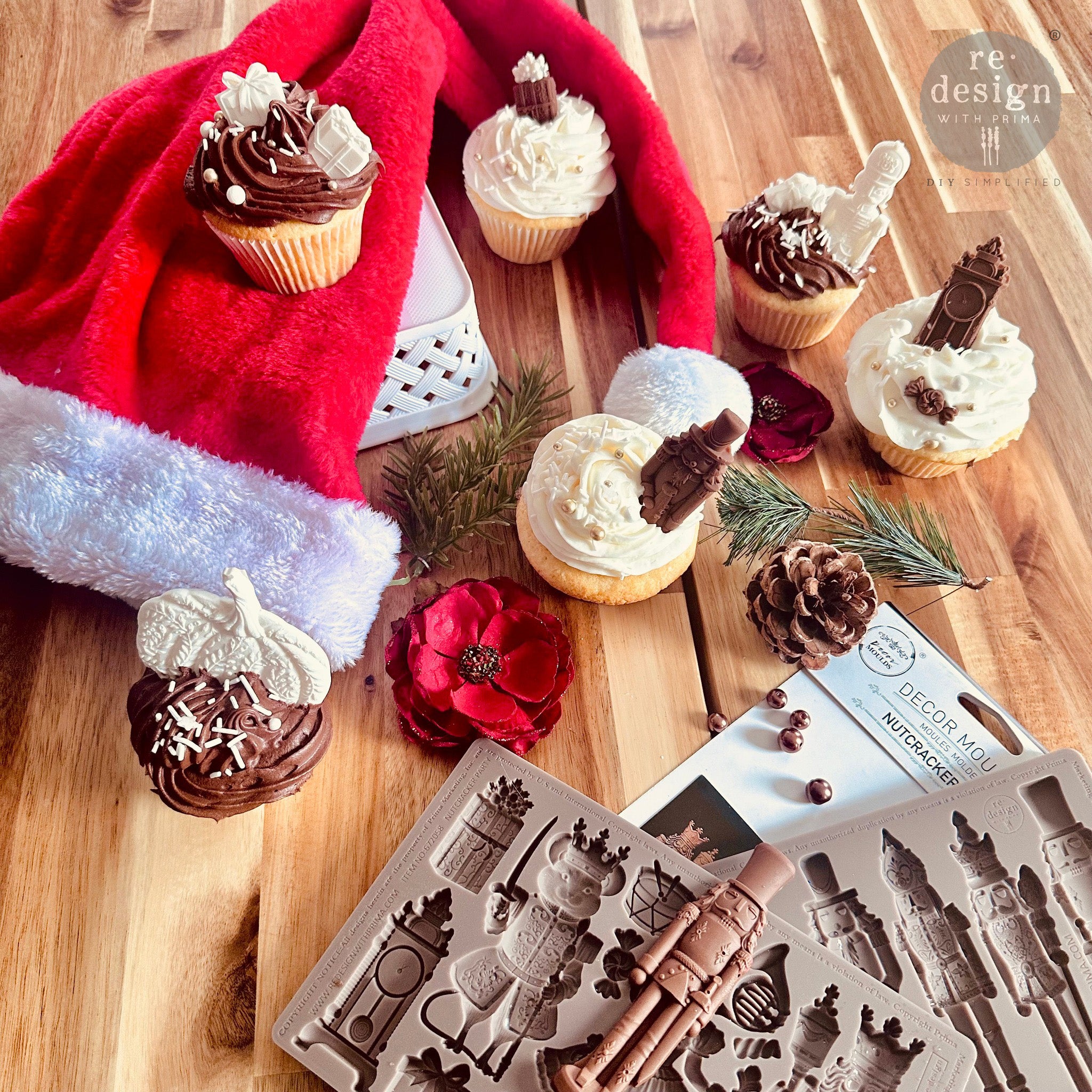 Cupcakes on a wood table with a Santa hat feature ReDesign with Prima's Nutcracker Party silicone mold castings made out of chocolate.