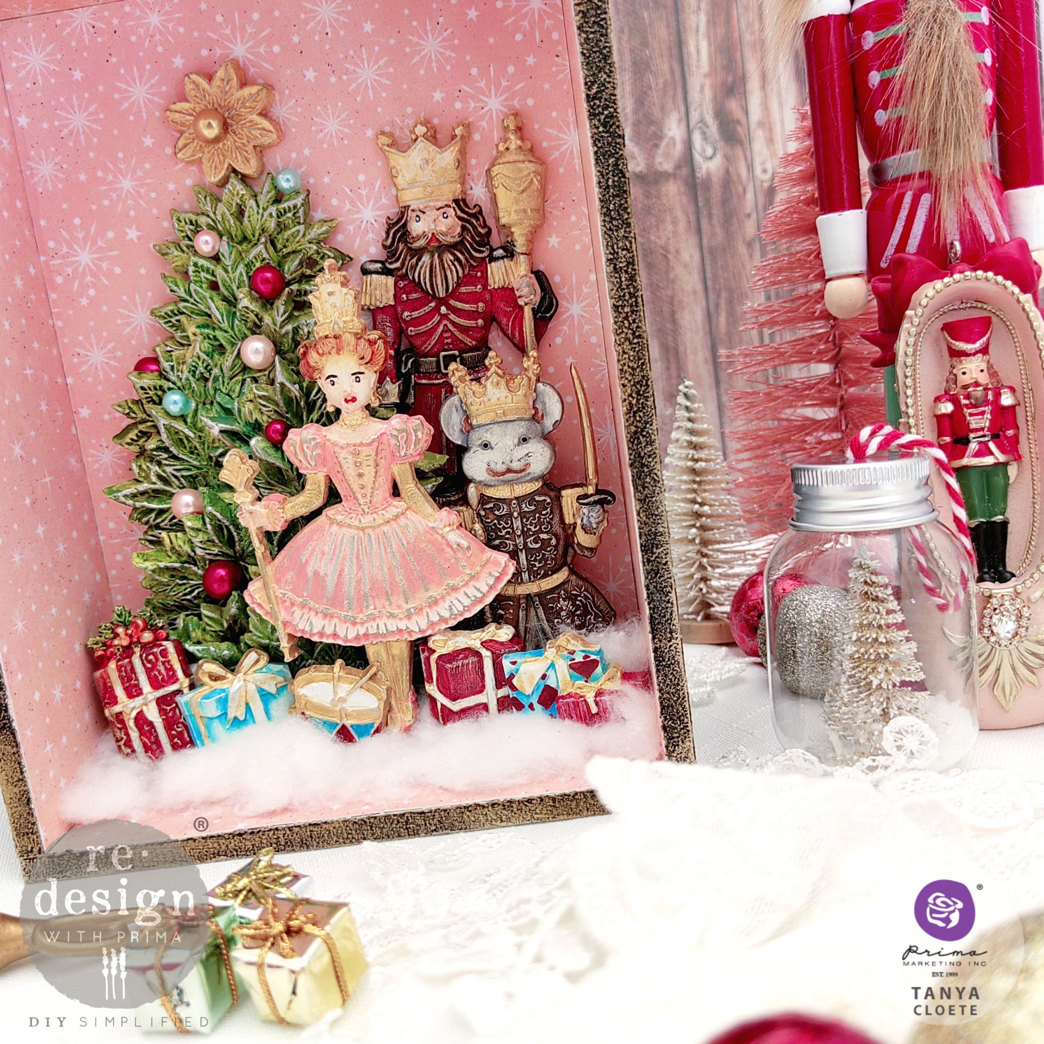 A shadow box painted pink with white starburst snowflakes feature colorful castings from ReDesign with Prima's Nutcracker Party silicone mold.