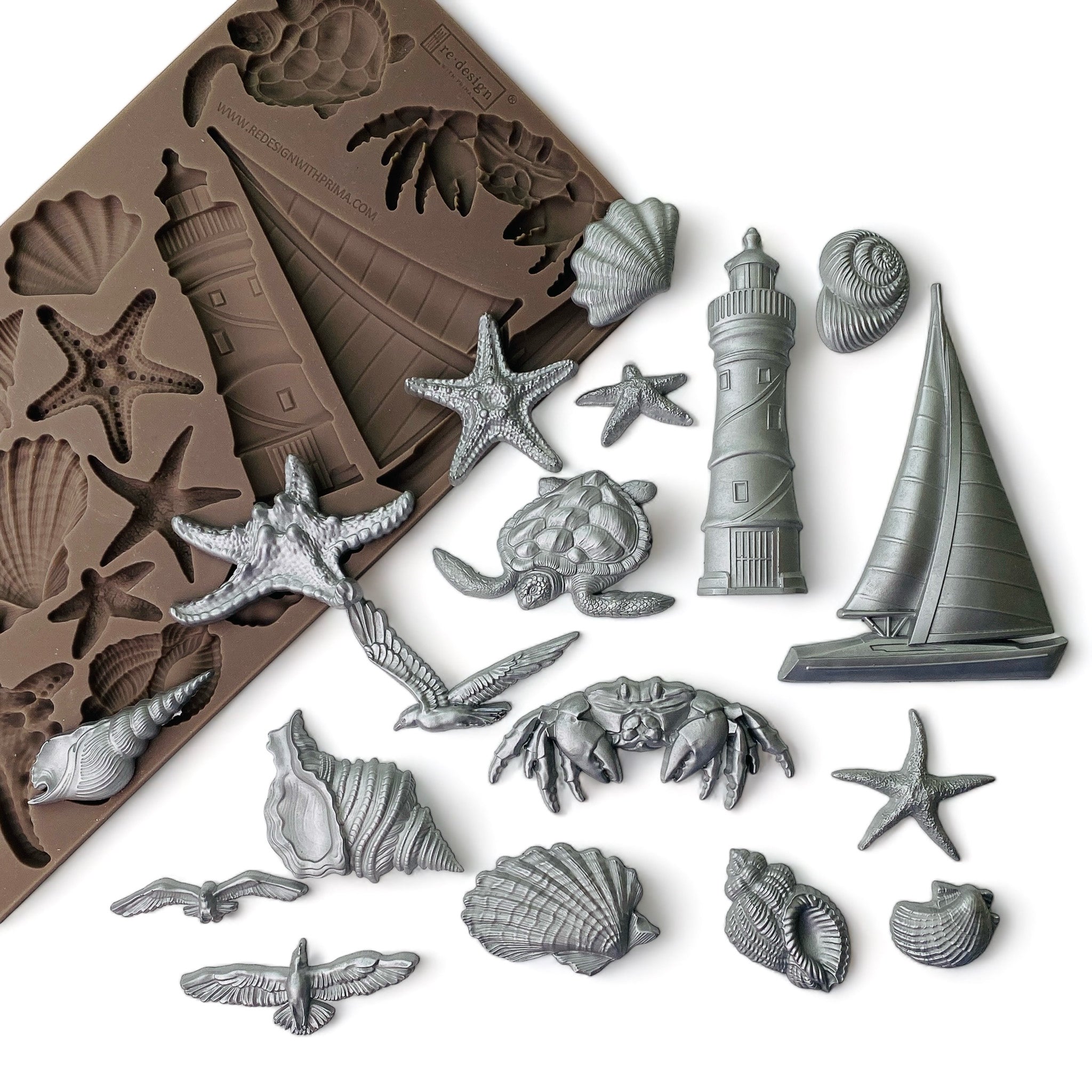 A brown silicone mold  and silver colored castings that features sailboats, sea shells, star fish, lighthouses, and more are against a white background.