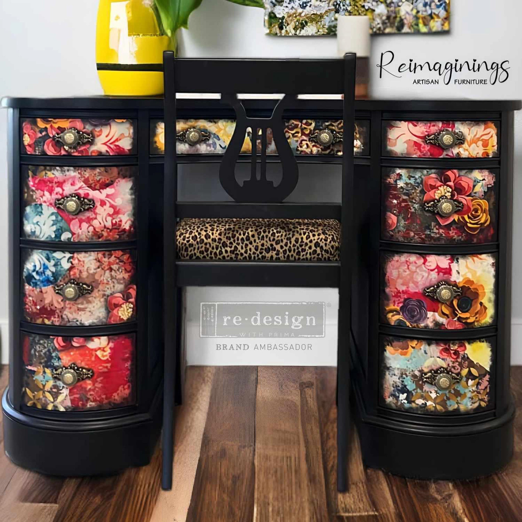 A vintage desk with 9 drawers refurbished by Reimaginings Artisan Furniture is painted black with colorful floral designs and features ReDesign with Prima's Soho Haven silicone mold on each drawer with the knobs.