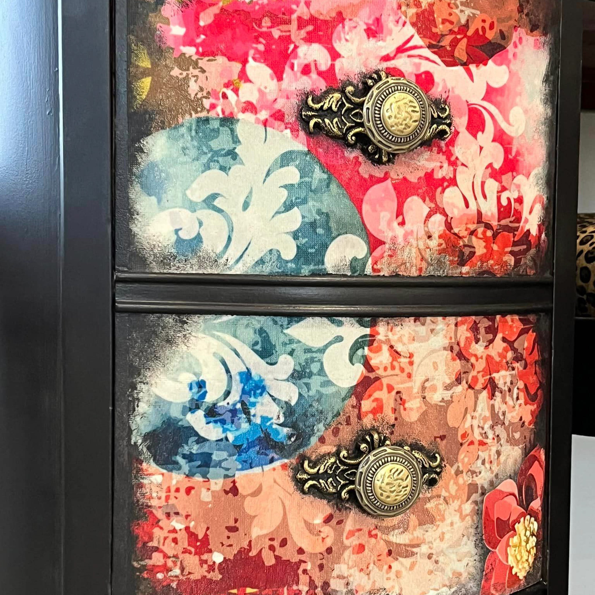 Close-up of a vintage desk with 9 drawers refurbished by Reimaginings Artisan Furniture is painted black with colorful floral designs and features ReDesign with Prima's Soho Haven silicone mold on each drawer with the knobs.