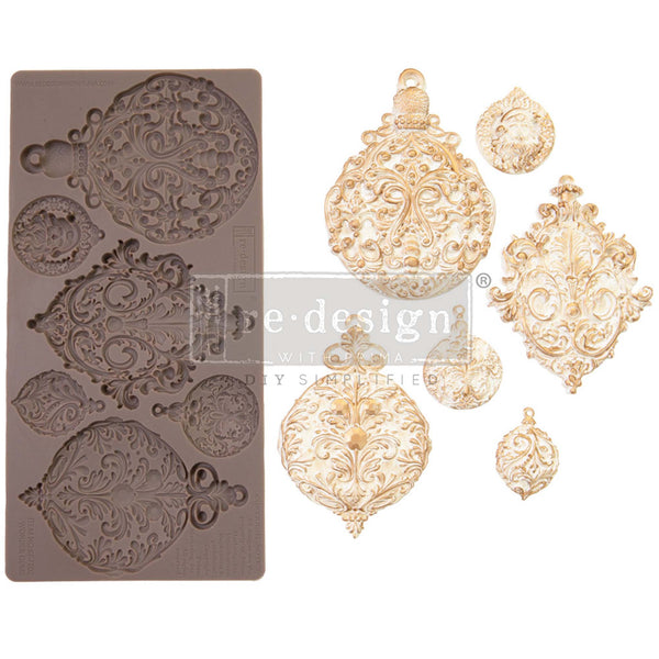A brown silicone mould and gold/white castings of 6 ornate ornaments are against a white background.