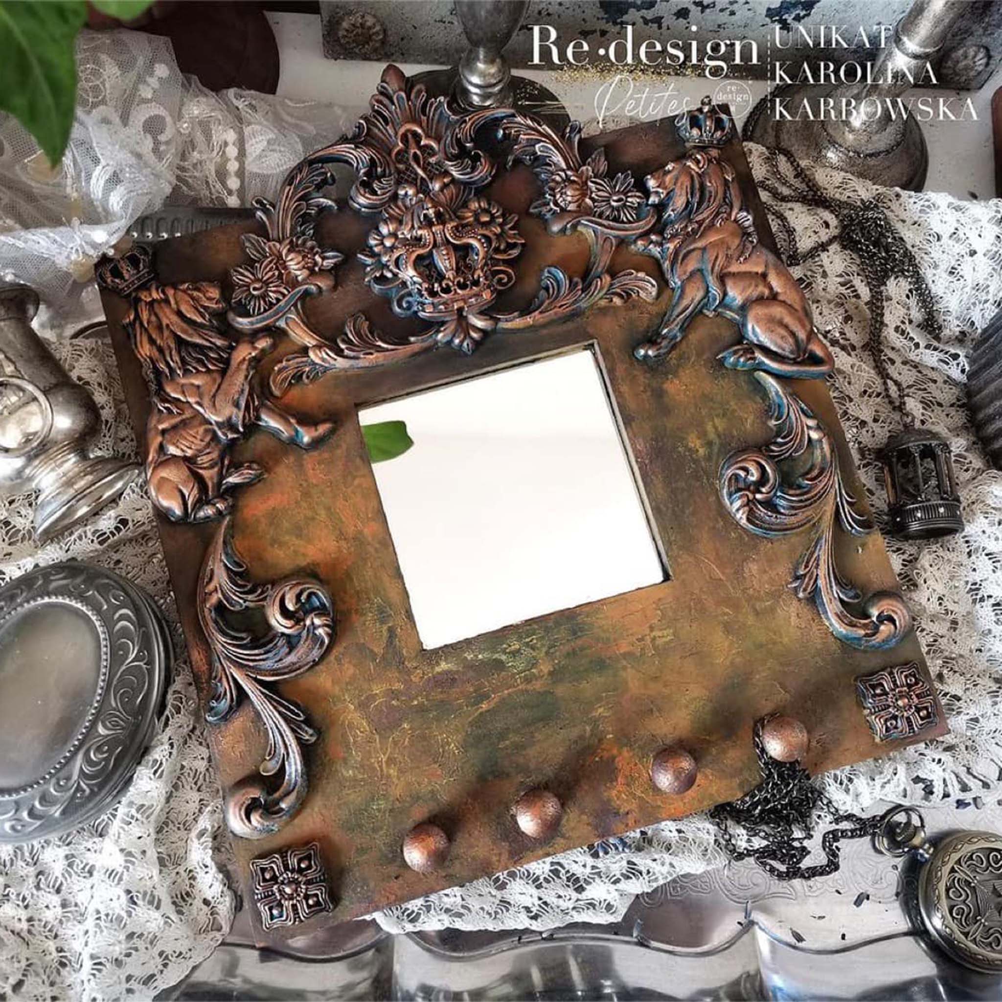 A wood mirror frame refurbished by a ReDesign with Prima Brand Ambasador features Claire and other silicone castings painted in a dark copper.