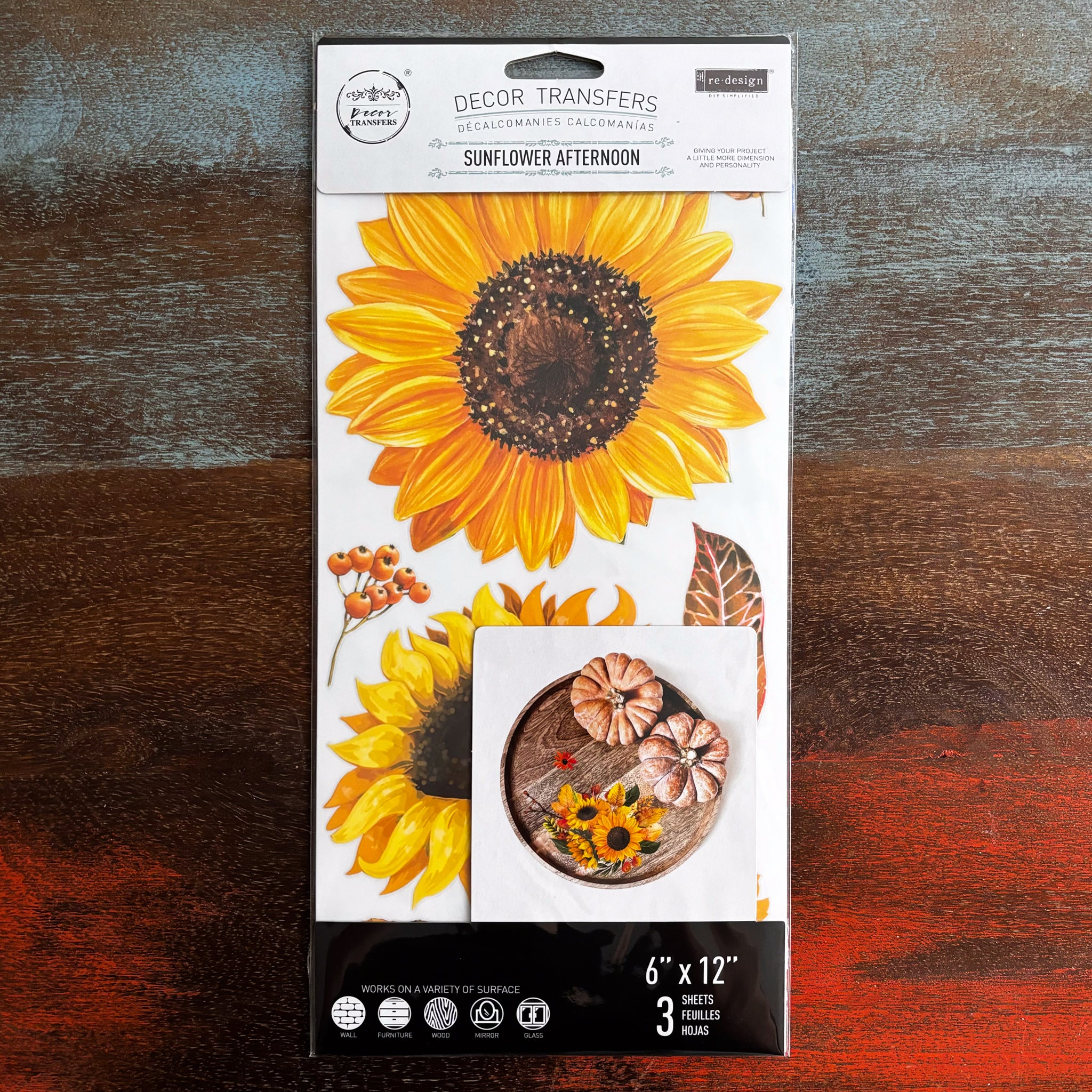 A package of ReDesign with Prima's Sunflower Afternoon small transfer is against a dark wood background.