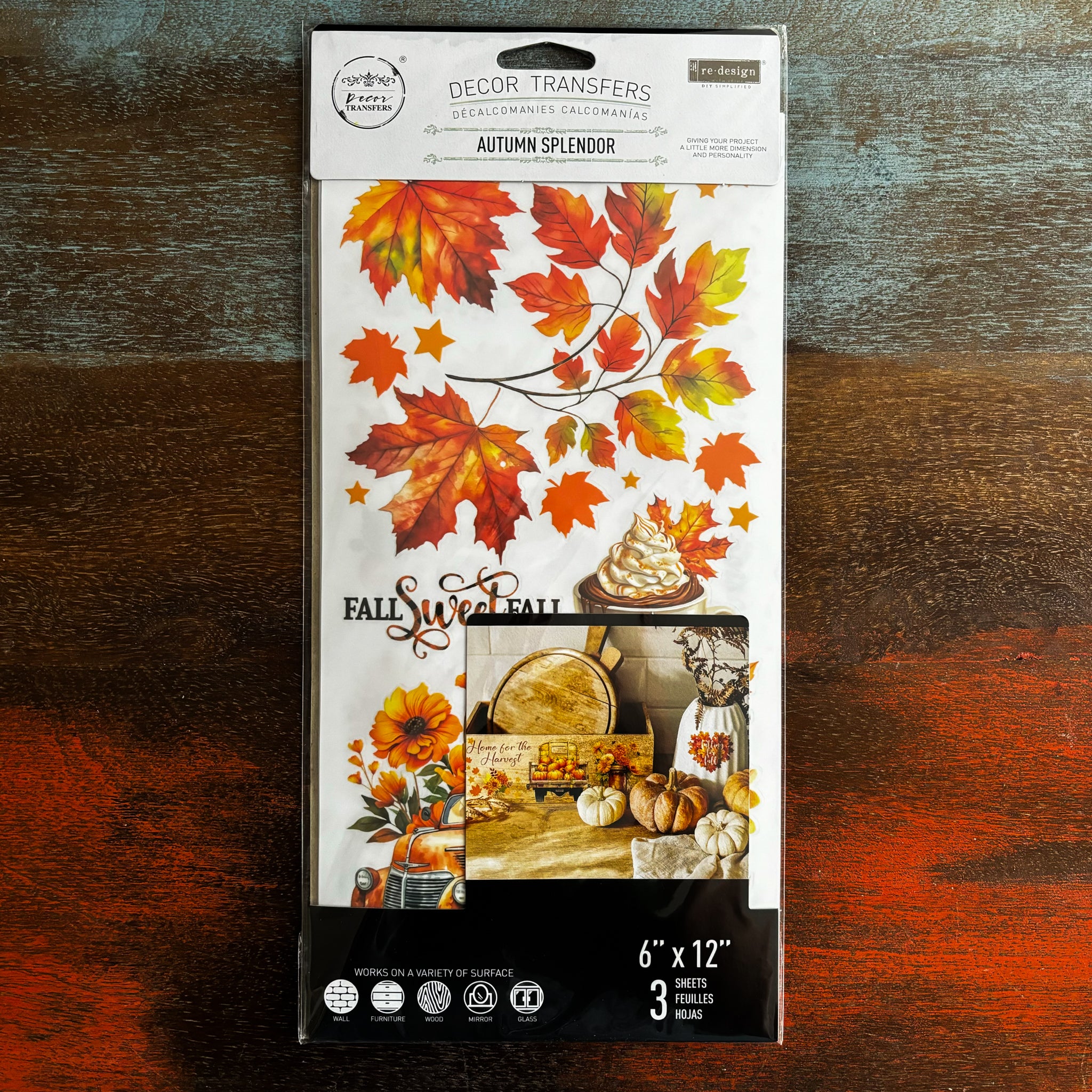 A package of ReDesign with Prima's Autumn Splendor small rub-on transfer is against a dark wood background.