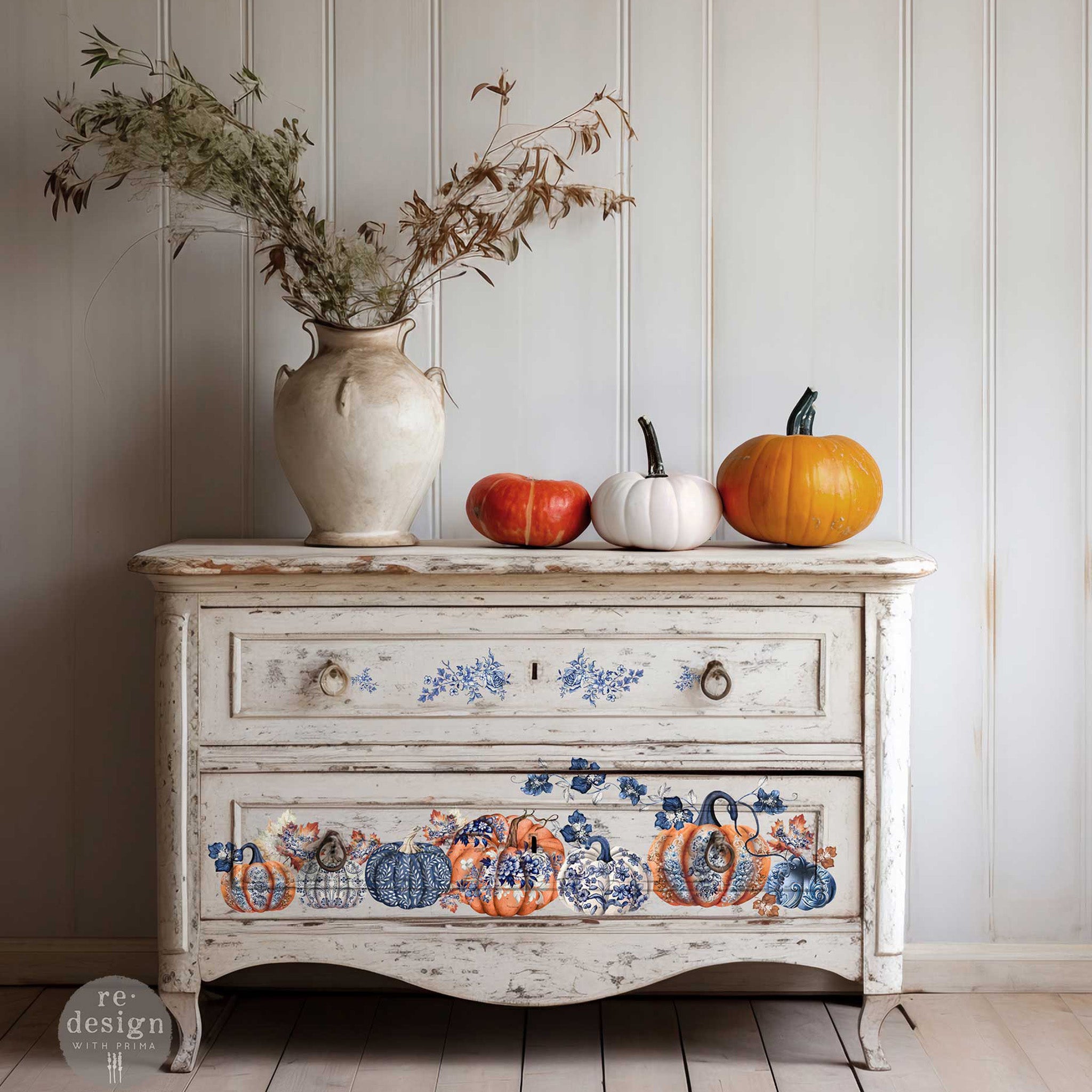 A vintage 2-drawer small dresser is painted soft white and features ReDesign with Prima's Pumpkin Patch Galore small rub on transfer on the drawers.