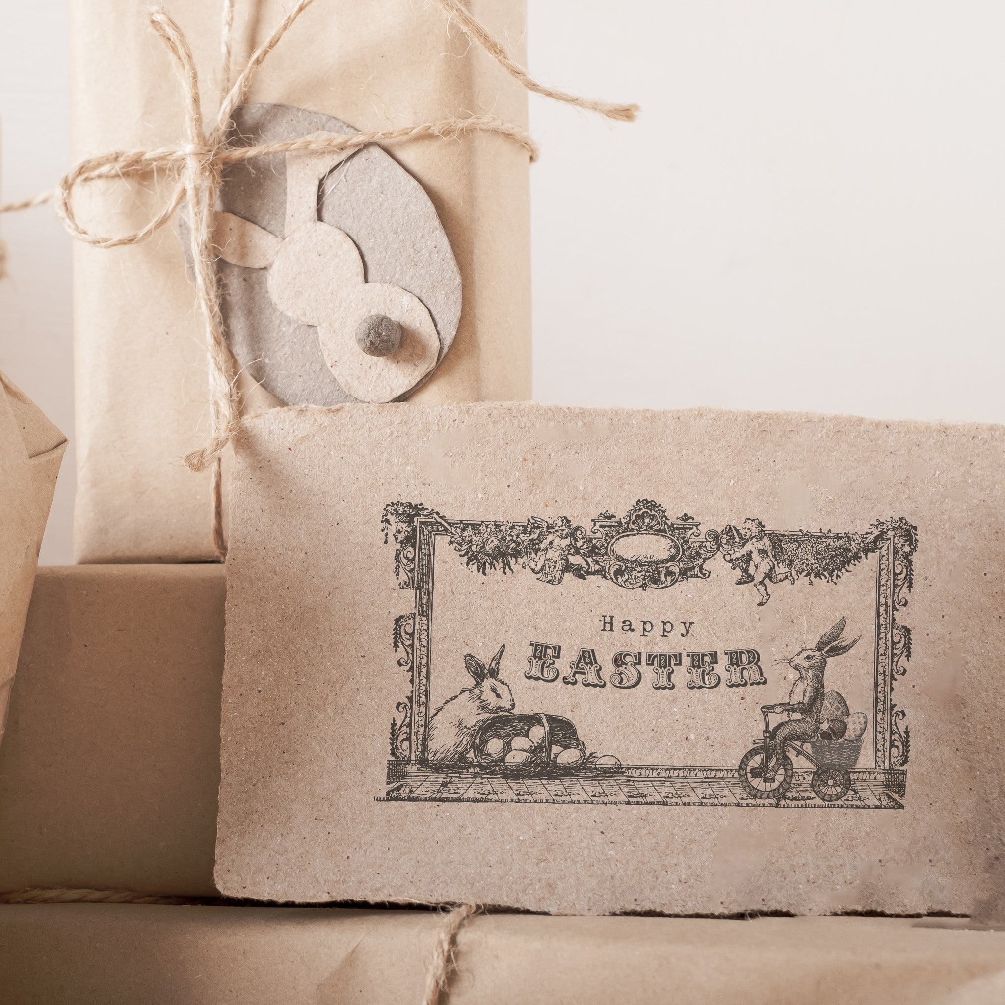 A handcut card that features a design of ReDesign with Prima's Easter Blessings stamp is sitting on brown paper wrapped gifts.