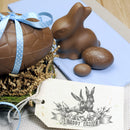 A chocolate bunny and eggs and a handmade gift tag that features 1 of ReDesign with Prima's Easter Blessings stamps are against a light blue table napkin.
