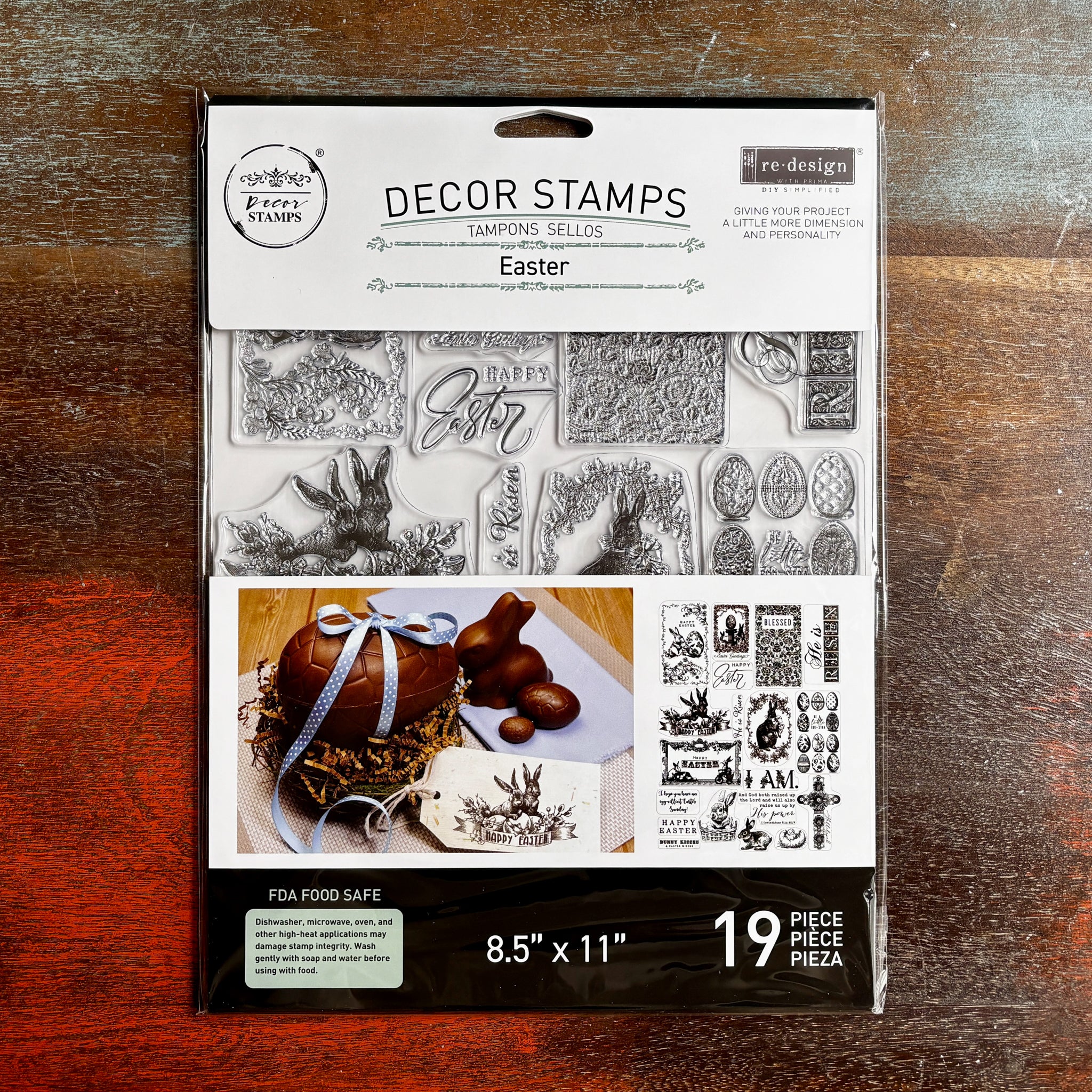 A package of ReDesign with Prima's Easter Blessings Decor Stamps is against a dark wood background.